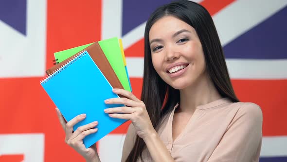 Asian Woman Showing Copybooks Against UK Flag, Scholarship for Foreign Students