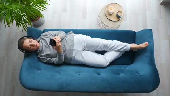 Woman in Wireless Headphones Moving Head From Side to Side While Listening to Music and Using Mobile