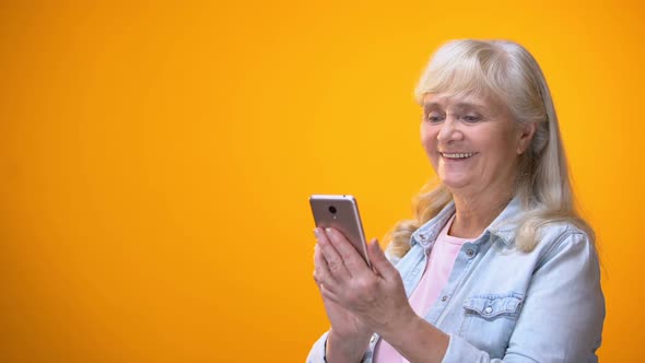 Happy Elderly Lady Scrolling on Smartphone