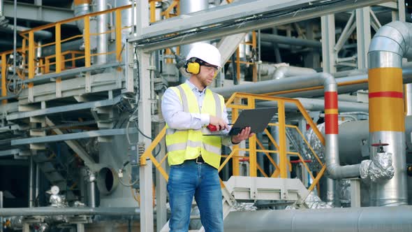 Male Employee is Talking Over the Radio on the Refinery Premises