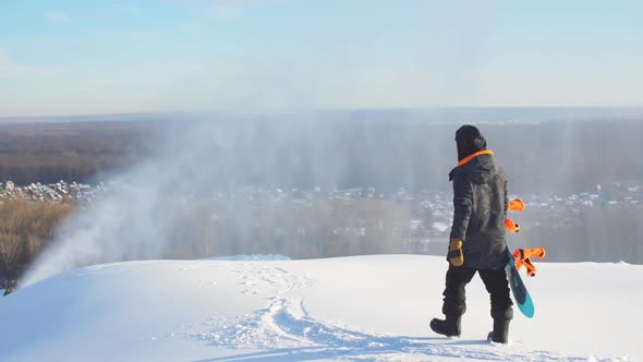 Pensive Guy Wit a Snowboard Walking on the Mountain