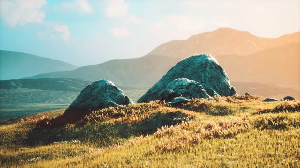 Meadow with Huge Stones Among the Grass on the Hillside at Sunset