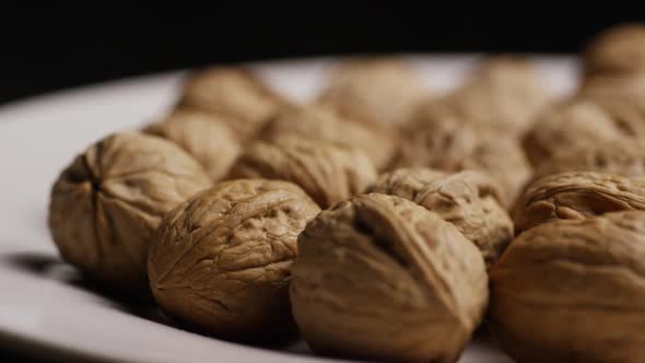 Cinematic, rotating shot of walnuts in their shells on a white surface - WALNUTS 