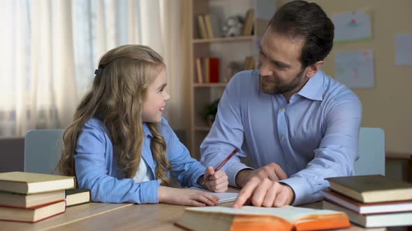 Attentive Father Helps His Little Daughter to Do Homework for School, Education