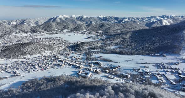 Aerial view of snow covered Bakuriani with beautiful snowy mountains around. Georgia 2021