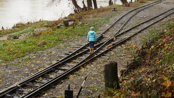 Girl Walking on Train Tracks. The Girl at the Crossroad. The Child Chooses the Way