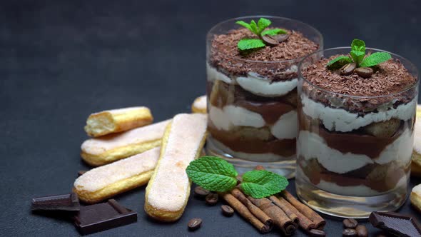 Classic Tiramisu Dessert in a Glass and Savoiardi Cookies on Dark Concrete Background
