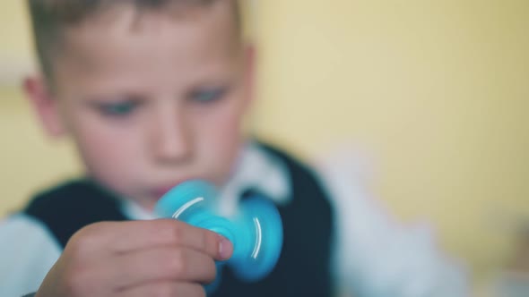 Little Boy Looks at Turning Spinner on Blurred Background