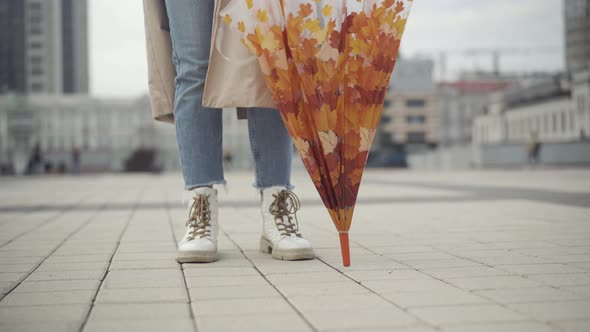 Unrecognizable Young Woman Standing on City Square with Closed Umbrella and Spinning Accessoire