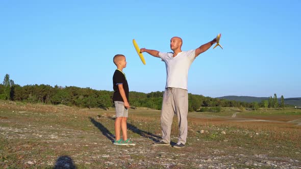 Dad Shows How to Fly Toy Plane to His Teenage Son in Nature at Sunset Time