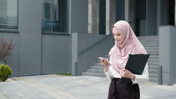 Muslim Business Lady with Mobile Standing Near Office Center