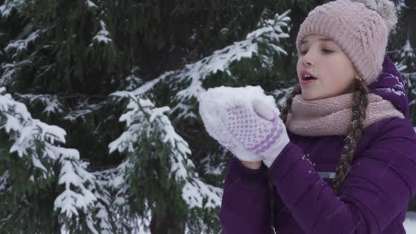 A Joyful Teenage Girl Blows on the Snow Having Fun in a Winter Park