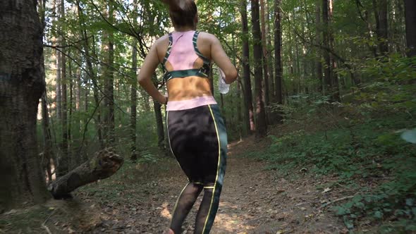 Gymnastic Girl Jogging in the Forest and Holding Water Bottle