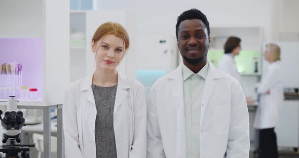 Portrait of Multiethnic Young Scientists Smiling at Camera in Modern Laboratory