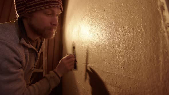 A handsome professional plasterer using a Japanese trowel for final smoothing