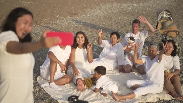 Cheerful Multigenerational Family Sitting in Sunlight on Rocky Mediterranean Sea Coast As Young