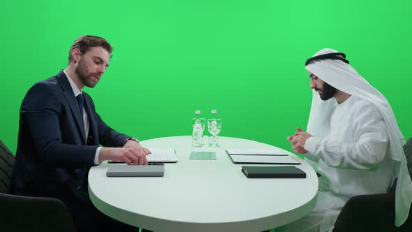 An Arab Man in a White Kandura Sign Financial Documents with a Partner Businessman in a Suit While