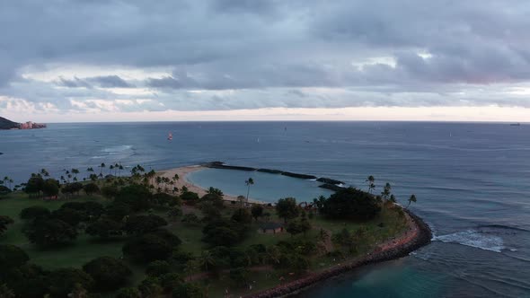 Tilt down aerial panning shot of Magic Beach in Honolulu, Hawaii at sunset. 4K