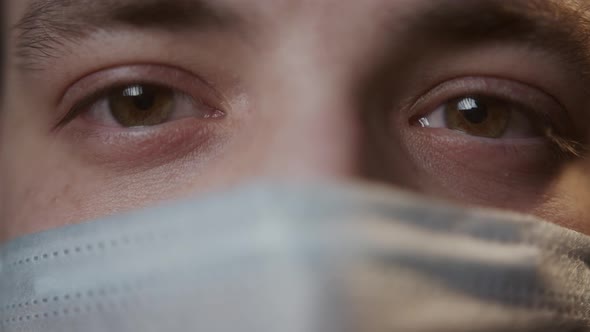 Closeup of Browneyed Young Man Wearing Medical Protective Mask Looking in Camera