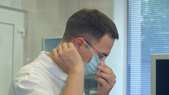 Young male doctor putting surgical hat on in a surgery room