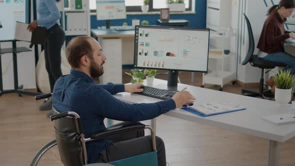 Paralyzed Business Man Writing Financial Report Talking with Colleague