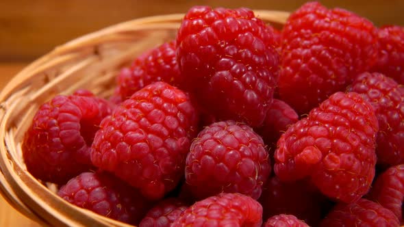 Hand Takes a Big Raspberries Out of Wicker Basket