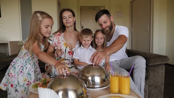 A Family with a Little Son and Twin Daughters Have Breakfast in a Hotel Room.