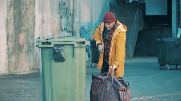 A Beggar is Looking Into a Waste Bin