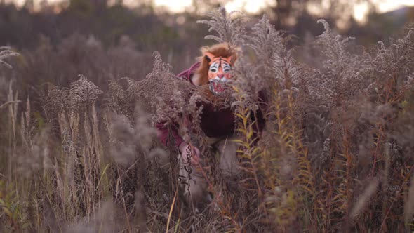 Through the Yellow Grass the Guy in a Tiger's Mask Slips Stops Runs Away  Slow Mo