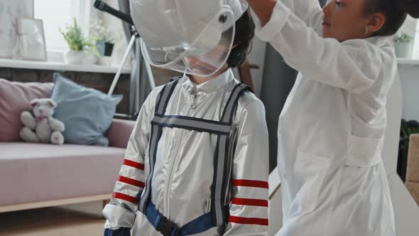 8-Year-Old Girl Putting Space Helmet on Boy