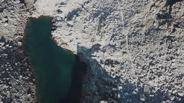 Top aerial view of an alpine lake next to rocky mountains, cabane d'Orny, switzerland, drone