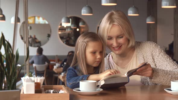 Mother and Daughter Read the Book at the Cafe