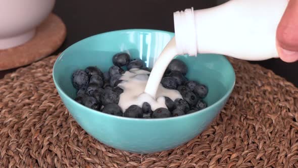 Man pouring yogurt into a plate with blueberries