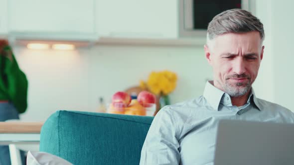 Displeased mature man working on laptop