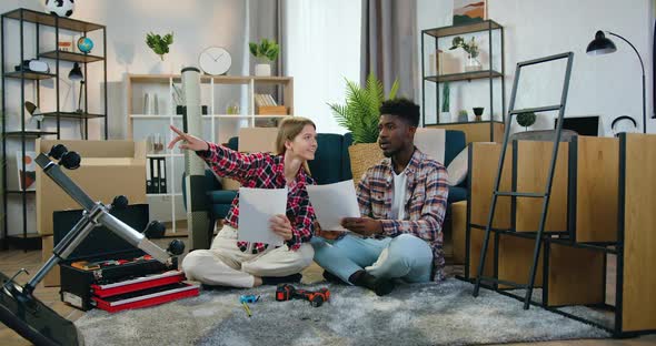 Couple Sitting Together on the Floor in Own House and Discussing Interior Design