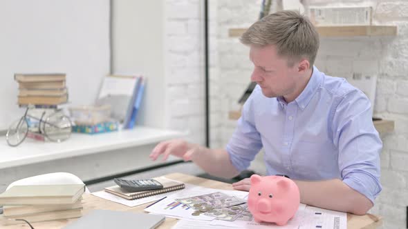 Businessman Saving Coins in Piggy Bank