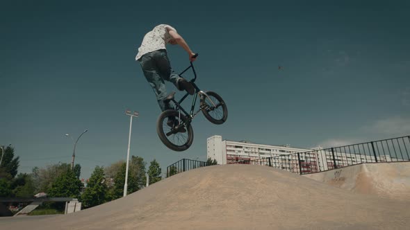 BMX Cyclist Extreme in the City Park Performs Dangerous Jumping Stunts