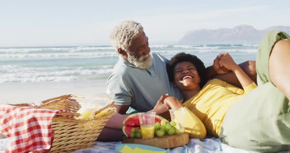 Happy african american couple having picnic on sunny beach