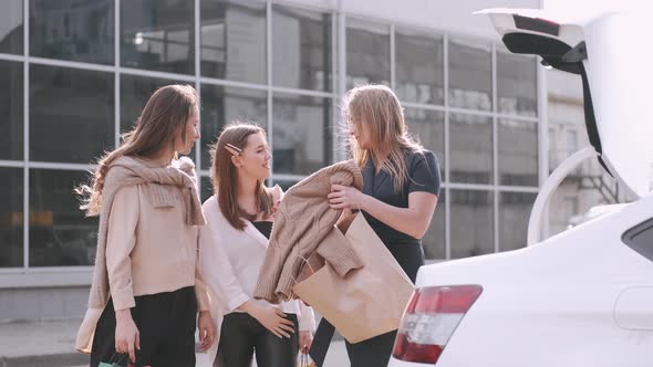 Happy Girlfriends Have Shopped and Putting Craft Shoppping Bags in a Car Trunk