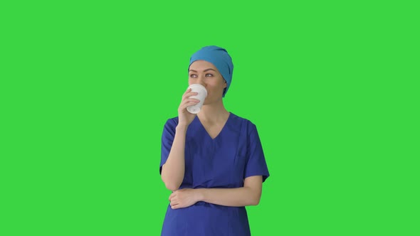 Smiling Female Doctor or Nurse in Blue Uniform Having a Coffee Break on a Green Screen, Chroma Key