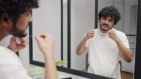 Curlyhaired Hindu Guy Takes Dental Floss to Clean Teeth