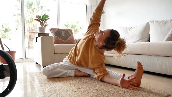 Fit woman sitting on floor and stretching body at home