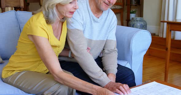 Senior couple discussing over bills on sofa