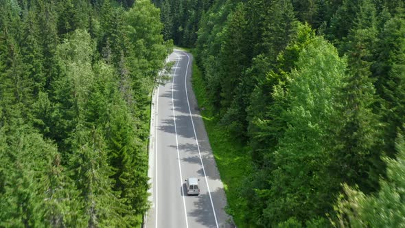 Aerial Follow Shot of a Delivery Car Driving Alone on Empty Forest Road