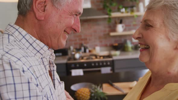 Senior Caucasian couple dancing and smiling in the kitchen