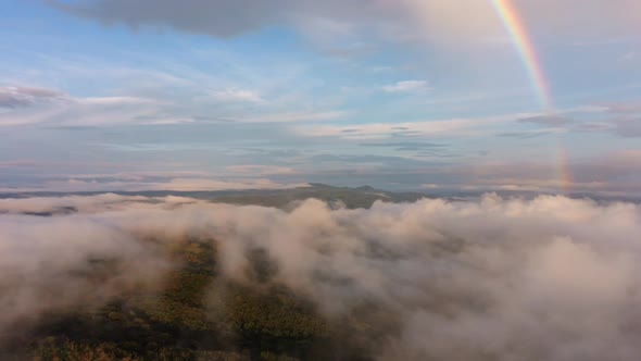 Mountains and hilltops peaking over low cloud cover with rainbow in the morning. Province of Guanaca