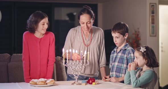 Kids and their mother lighting Hanukka candles