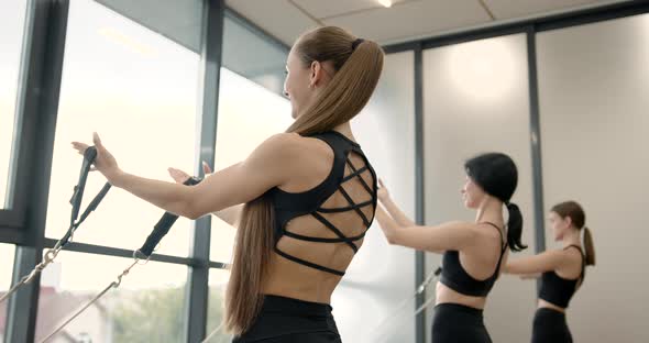 Three Women Doing Pilates on a Reformer Bed