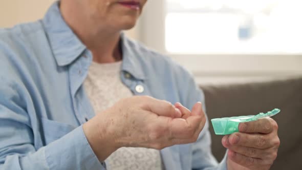 Mature Woman Laying Out Her Pills in a Small Weekly Pillbox