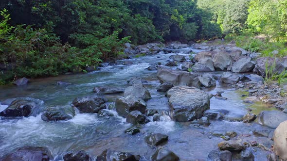 Water running through rocks in Rio Higuero at La Cuaba. Aerial forward and low altitude